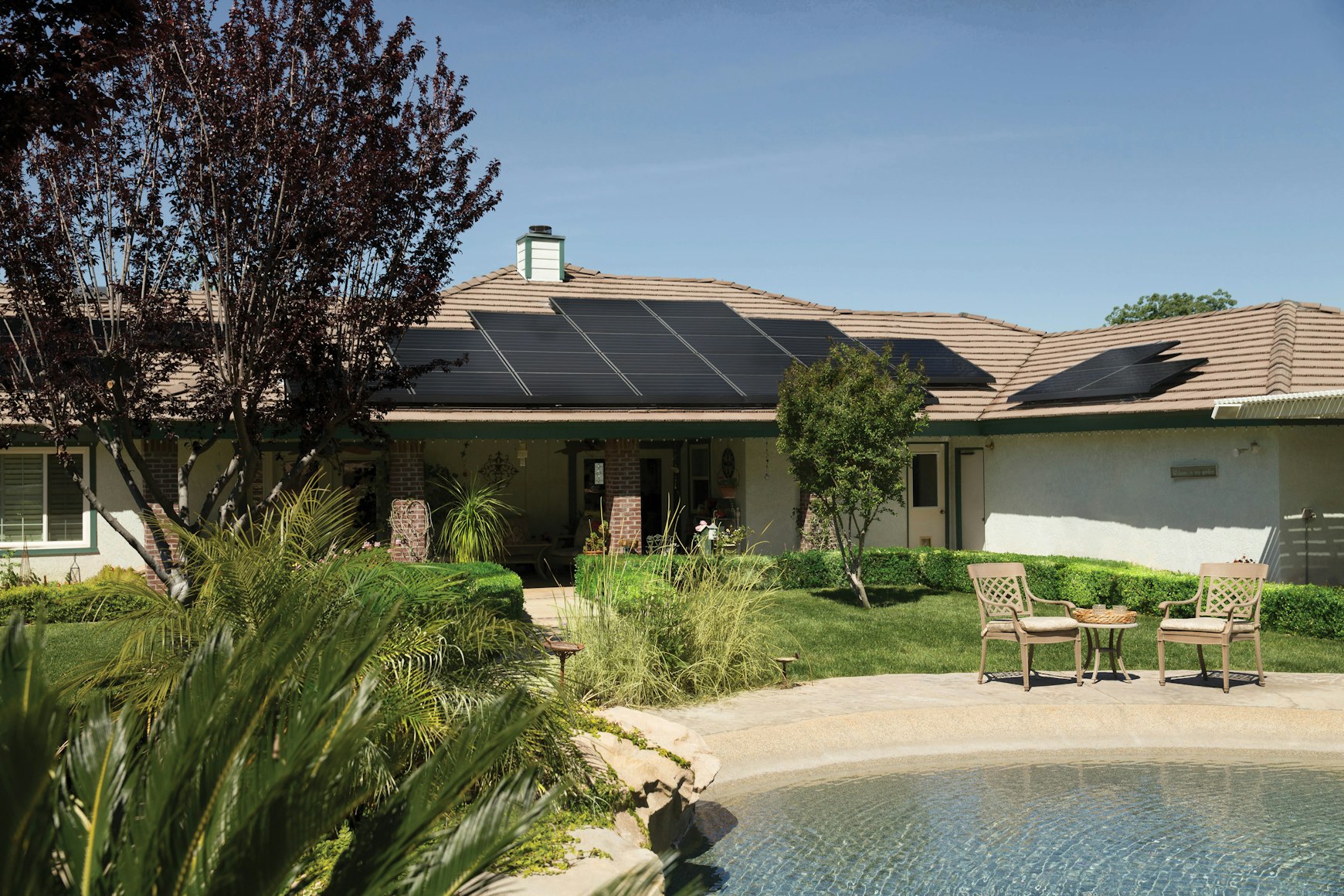 Panneaux solaires sur le toit d’une maison avec jardin et piscine