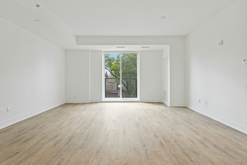 Pièce vide et lumineuse avec parquet clair et grande baie vitrée