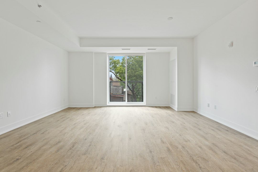 Pièce vide et lumineuse avec parquet clair et grande baie vitrée